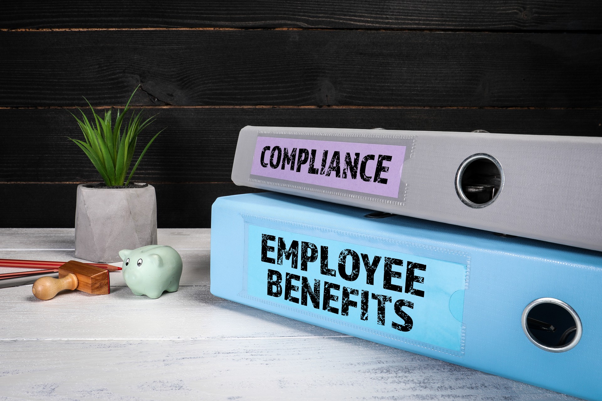 EMPLOYEE BENEFITS and COMPLIANCE. Document binders, folders on a wooden office desk